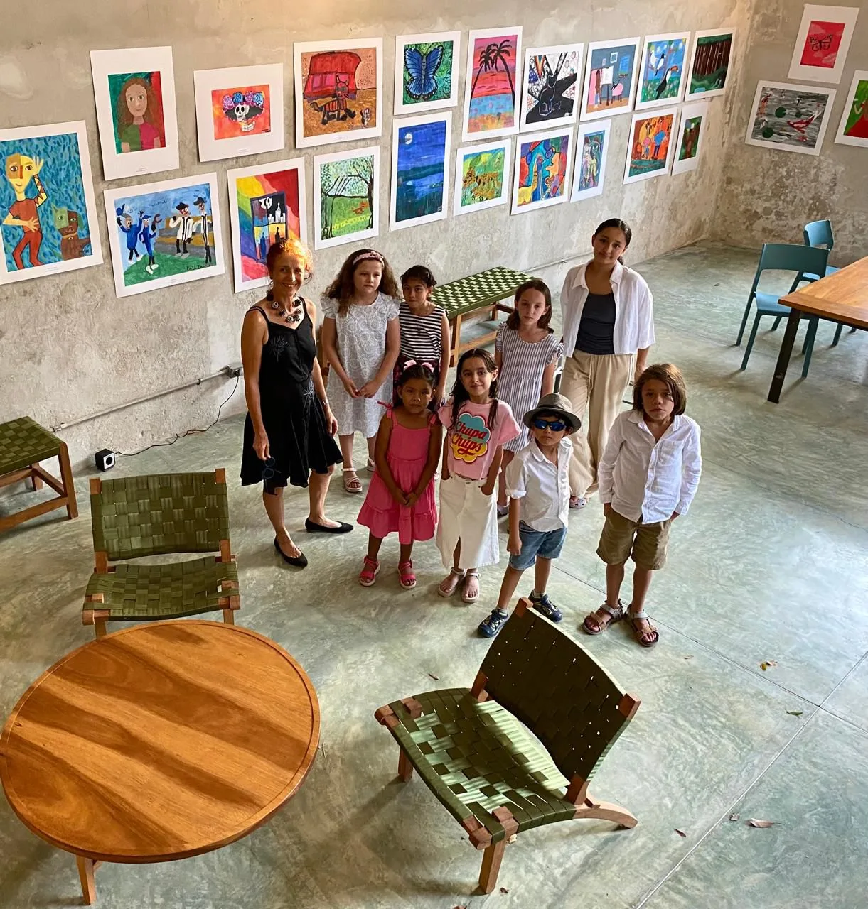 Grupo de alumnos posando con sus obras colgadas en la pared